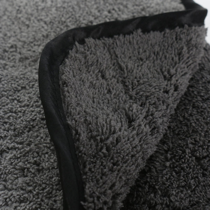Close-up of a textured grey microfibre towel with a black border on a white background