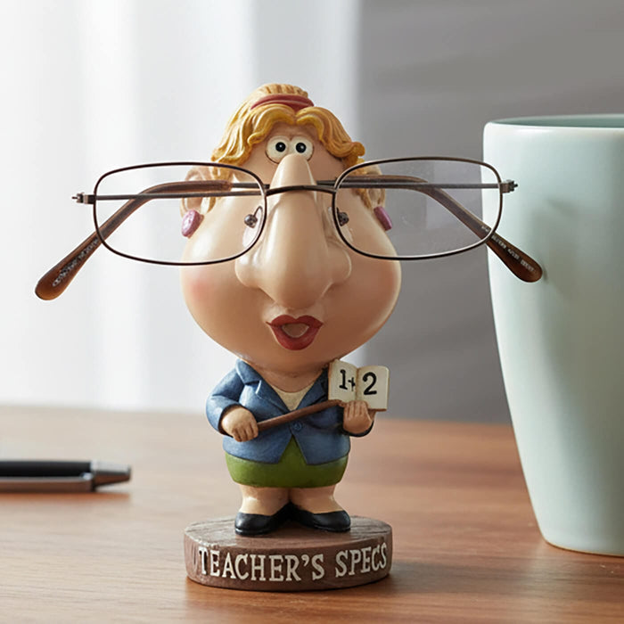 Teacher's Specs novelty figure glasses holder on a desk with blue coffee mug